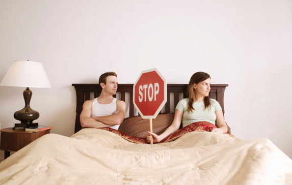 Couple holding stop sign in bed